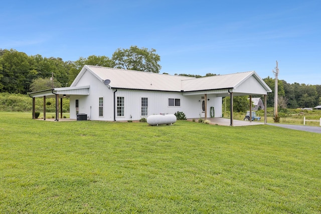 rear view of property featuring a carport, cooling unit, and a lawn