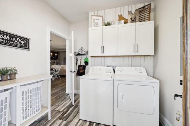 clothes washing area with cabinets, dark wood-type flooring, and washing machine and clothes dryer