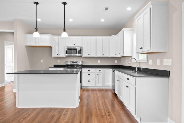 kitchen with appliances with stainless steel finishes, pendant lighting, and white cabinets