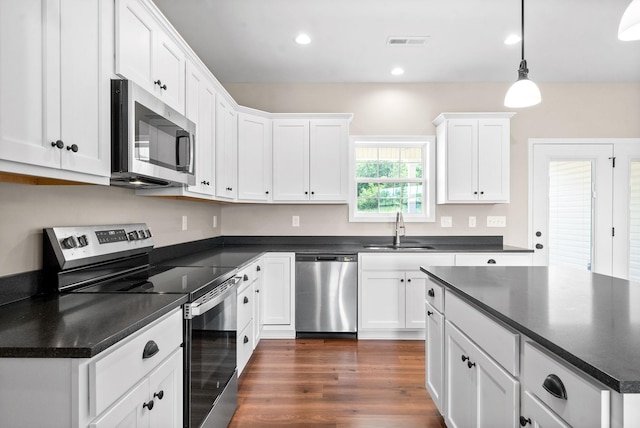 kitchen featuring pendant lighting, sink, dark wood-type flooring, stainless steel appliances, and white cabinets