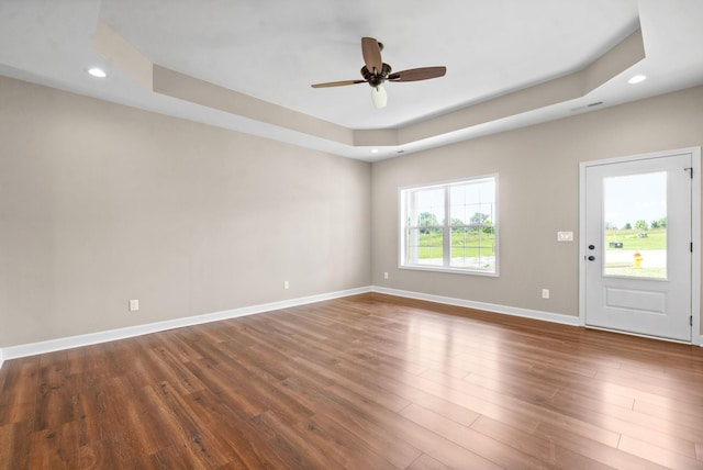 interior space featuring a raised ceiling, ceiling fan, and dark hardwood / wood-style flooring