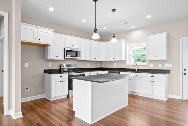 kitchen featuring appliances with stainless steel finishes, hanging light fixtures, a kitchen island, and white cabinets