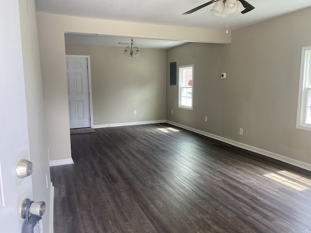 empty room with ceiling fan with notable chandelier and dark hardwood / wood-style floors