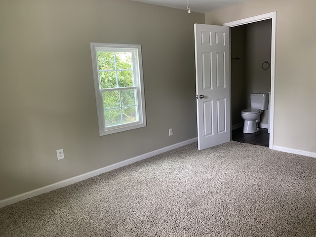 unfurnished bedroom featuring ensuite bathroom and carpet flooring