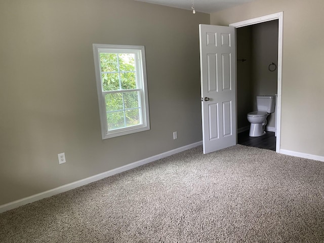 unfurnished bedroom with ensuite bathroom, carpet flooring, and baseboards