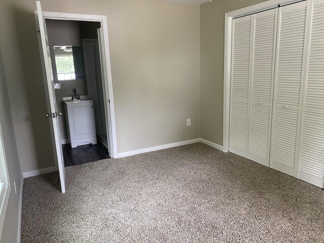 unfurnished bedroom featuring sink, a closet, and dark colored carpet