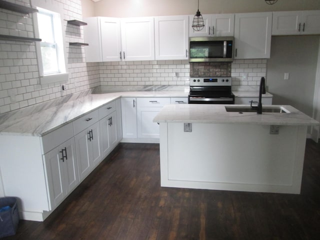 kitchen featuring appliances with stainless steel finishes, pendant lighting, white cabinetry, sink, and backsplash