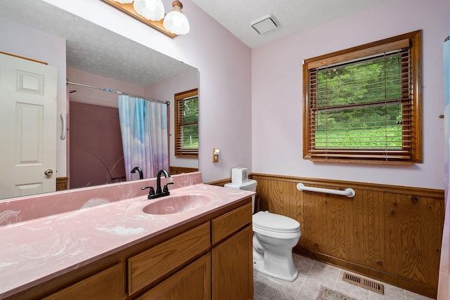 bathroom with wood walls, vanity, toilet, a textured ceiling, and a shower with shower curtain