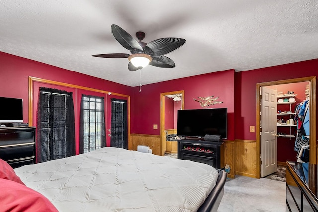 carpeted bedroom with ceiling fan, wooden walls, and a textured ceiling