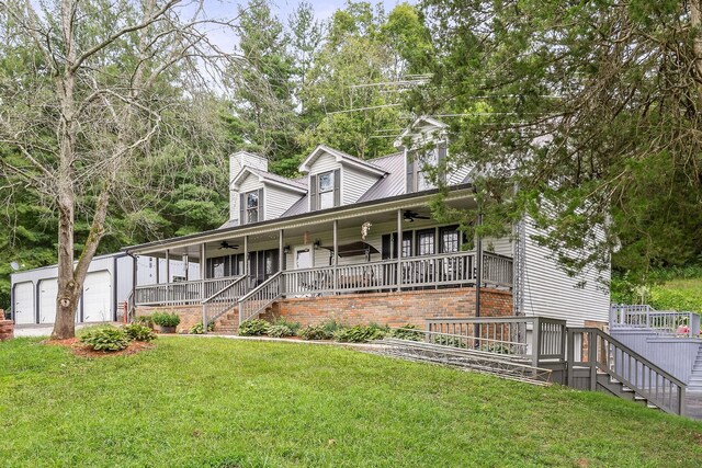 view of front of house with a garage, an outbuilding, ceiling fan, covered porch, and a front lawn