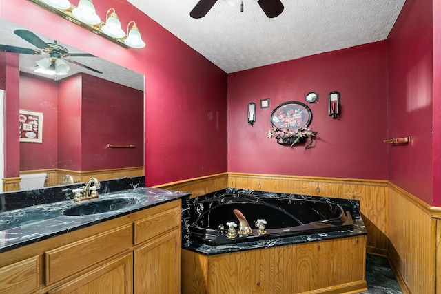 bathroom featuring vanity, a washtub, ceiling fan, and a textured ceiling