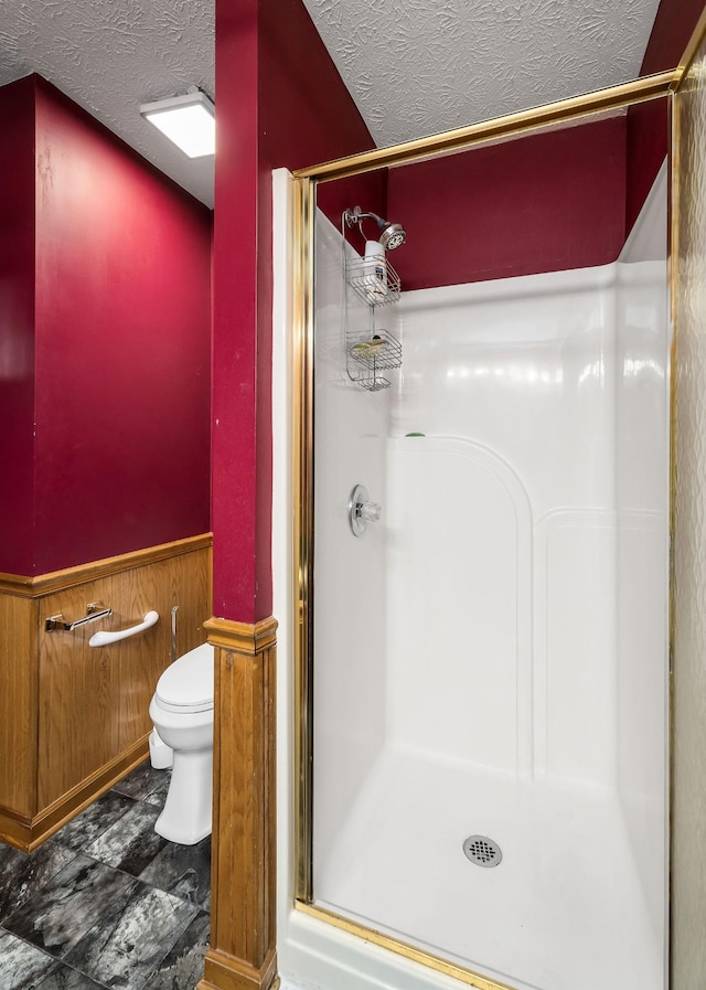 bathroom featuring walk in shower, toilet, and a textured ceiling