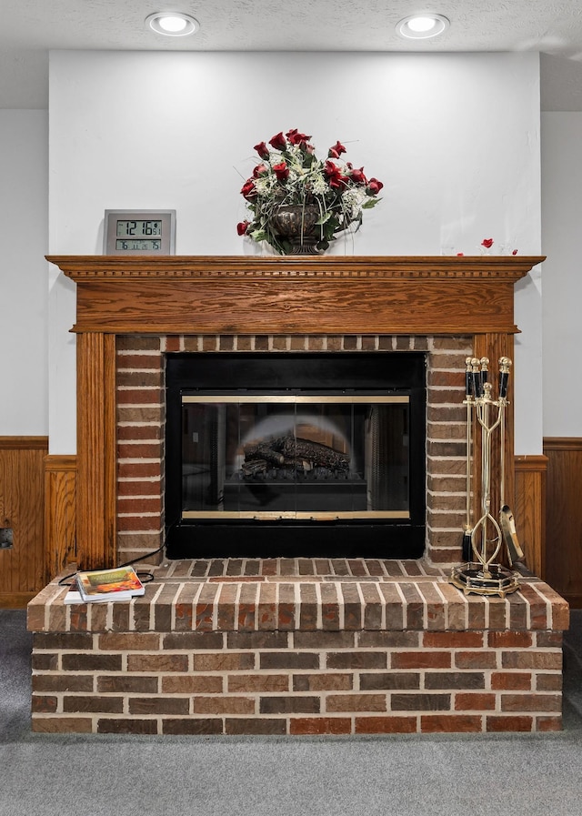 details with wooden walls, a textured ceiling, and a fireplace