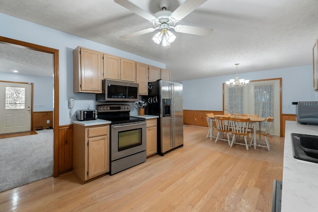 kitchen featuring appliances with stainless steel finishes, pendant lighting, light brown cabinetry, light hardwood / wood-style floors, and a textured ceiling