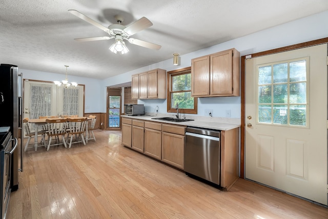 kitchen with stainless steel appliances, hanging light fixtures, sink, and light wood-type flooring