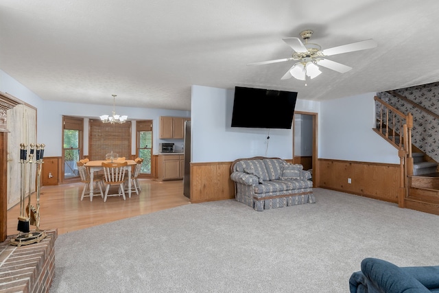 carpeted living room with ceiling fan with notable chandelier, a textured ceiling, and wood walls