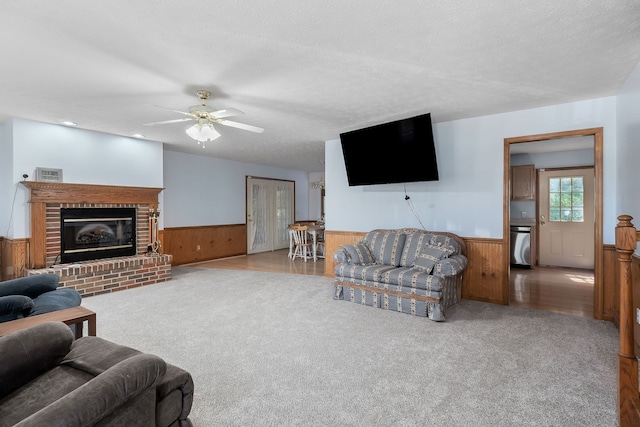 carpeted living room with a fireplace, a textured ceiling, and wood walls