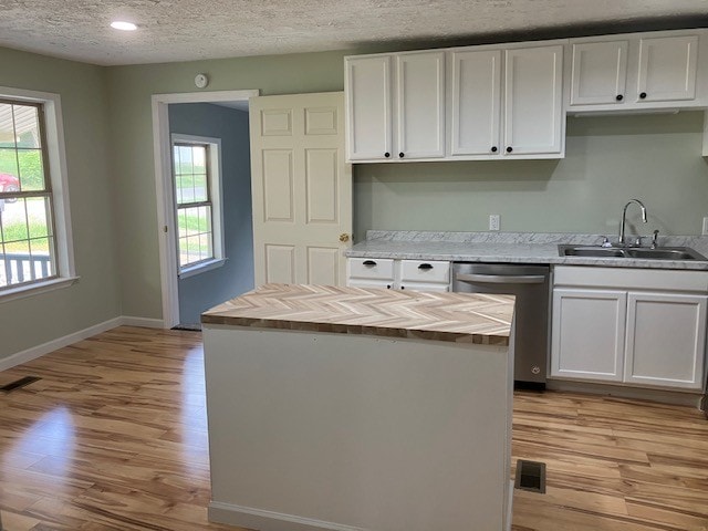 kitchen with sink, dishwasher, a healthy amount of sunlight, and white cabinetry