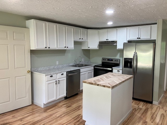 kitchen with white cabinets, stainless steel appliances, light wood-type flooring, a center island, and sink