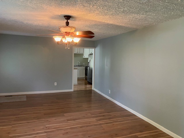 unfurnished room with sink, a textured ceiling, ceiling fan, and dark hardwood / wood-style floors