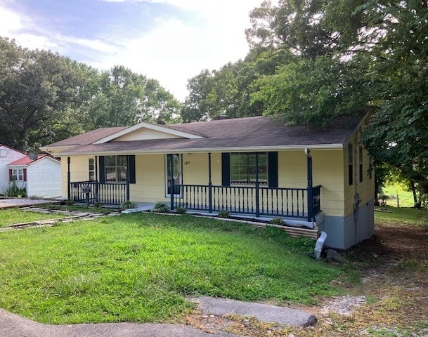 ranch-style home with covered porch and a front yard