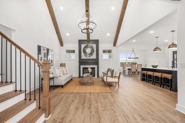 living room featuring a chandelier, sink, beamed ceiling, and light hardwood / wood-style floors