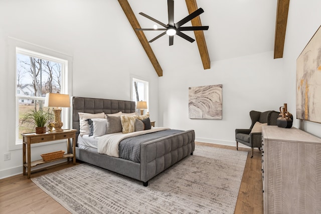 bedroom with ceiling fan, high vaulted ceiling, multiple windows, light hardwood / wood-style flooring, and beamed ceiling