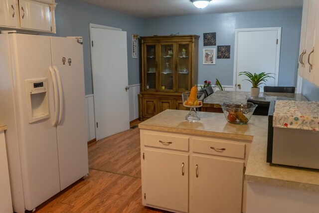 kitchen with white refrigerator with ice dispenser, light wood-type flooring, and white cabinets