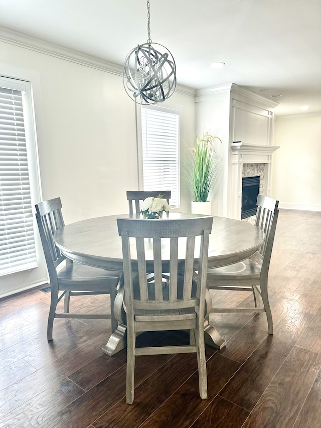 dining area with ornamental molding, hardwood / wood-style floors, a fireplace, and a chandelier