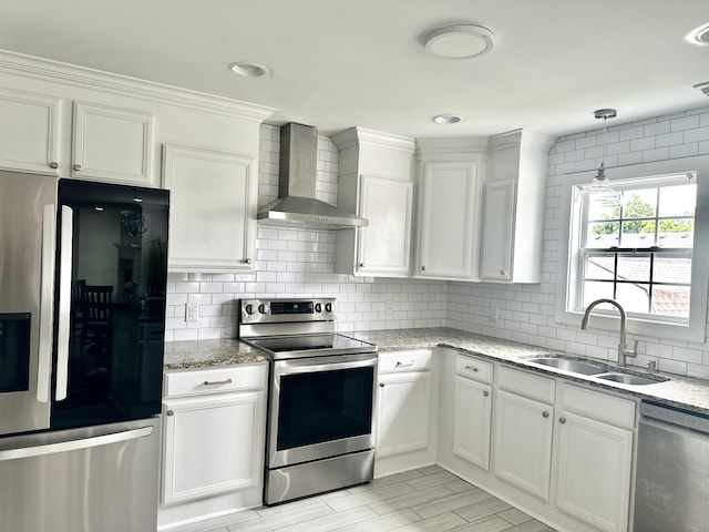 kitchen featuring appliances with stainless steel finishes, sink, hanging light fixtures, white cabinetry, and wall chimney exhaust hood