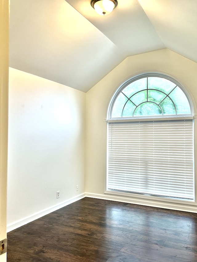 empty room with dark wood-type flooring and vaulted ceiling