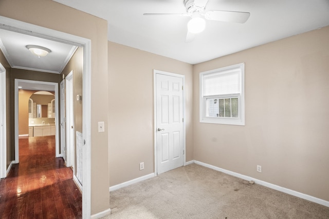 unfurnished bedroom featuring ceiling fan, a closet, wood-type flooring, and ornamental molding