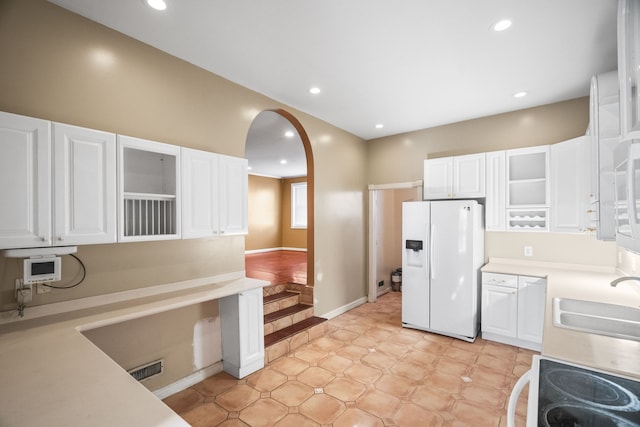 kitchen with white cabinets, white refrigerator with ice dispenser, sink, and range