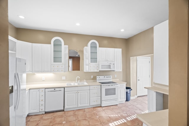 kitchen with sink, white cabinets, light tile patterned flooring, and white appliances