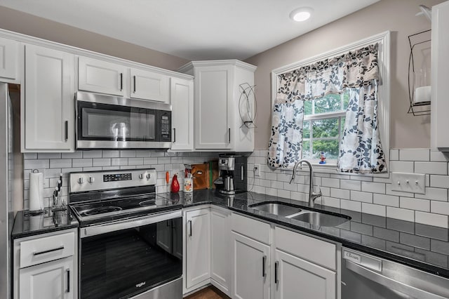 kitchen featuring sink, white cabinetry, tasteful backsplash, dark stone counters, and stainless steel appliances