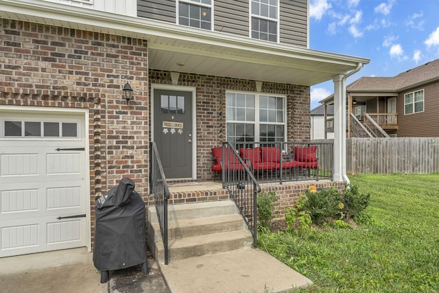 entrance to property with a garage, a yard, and covered porch