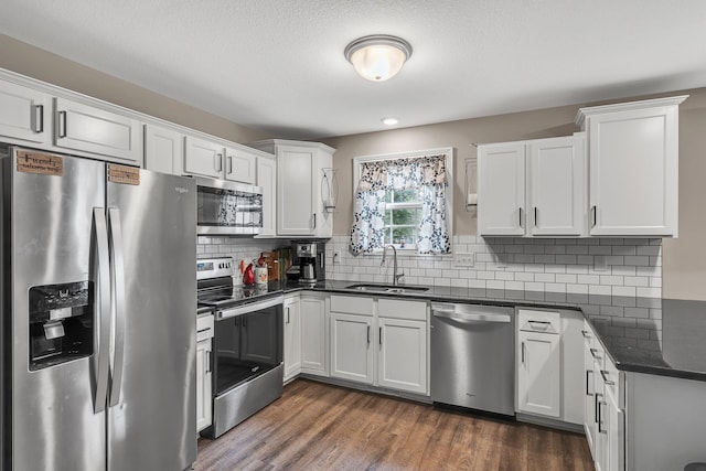 kitchen with sink, white cabinetry, tasteful backsplash, appliances with stainless steel finishes, and dark hardwood / wood-style flooring