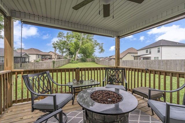 wooden deck featuring a yard, ceiling fan, and a fire pit