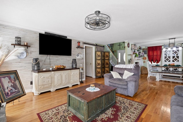 living room featuring wood-type flooring, a barn door, and a chandelier