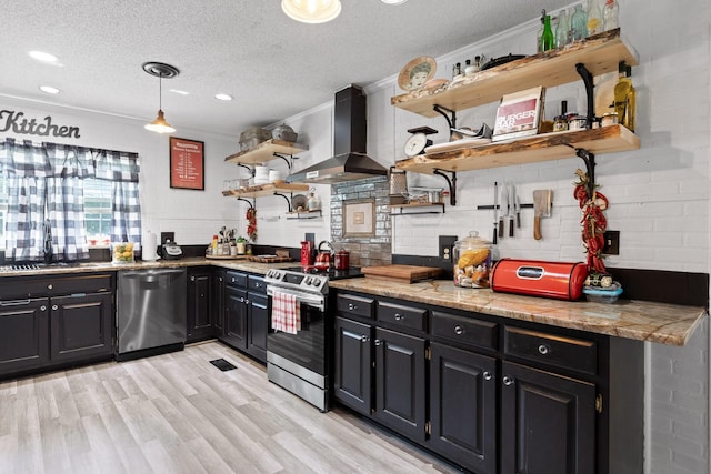 kitchen with decorative light fixtures, a textured ceiling, appliances with stainless steel finishes, light hardwood / wood-style floors, and wall chimney range hood