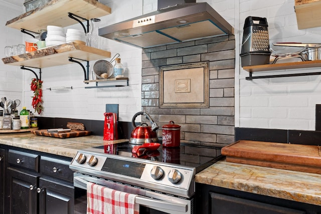 kitchen with stainless steel electric stove, light stone countertops, extractor fan, and decorative backsplash