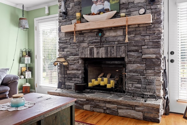 interior space featuring ornamental molding, a stone fireplace, and light wood-type flooring