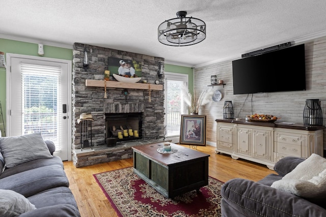 living room featuring a fireplace, crown molding, a wealth of natural light, and light hardwood / wood-style floors