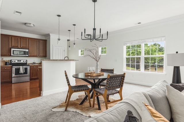 dining area with wood-type flooring, crown molding, and an inviting chandelier