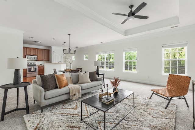 living room with a tray ceiling, light carpet, ceiling fan, and ornamental molding