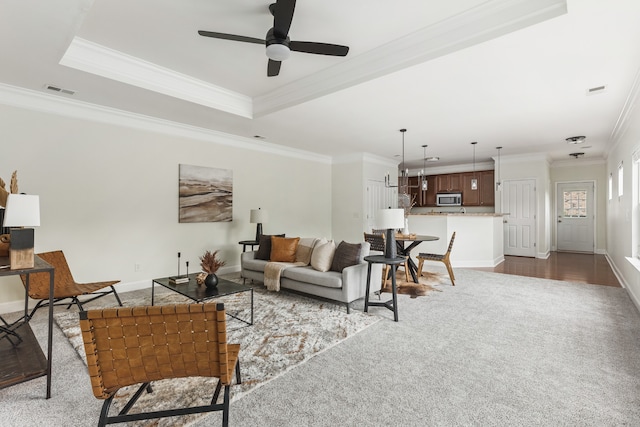 living room featuring wood-type flooring, crown molding, a raised ceiling, and ceiling fan