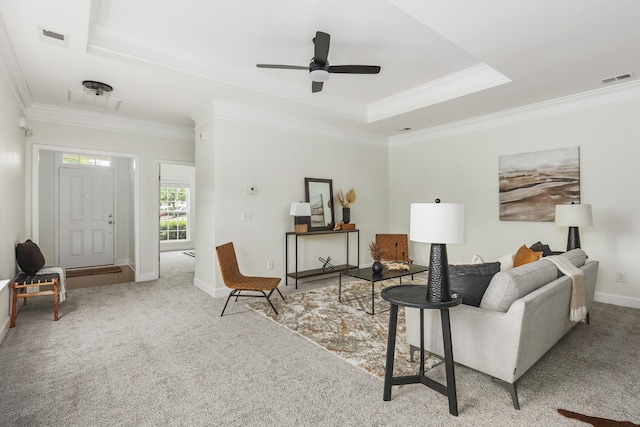 living room featuring ceiling fan, light colored carpet, crown molding, and a tray ceiling