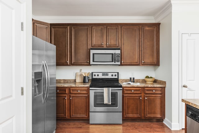 kitchen with appliances with stainless steel finishes, dark hardwood / wood-style flooring, and light stone counters