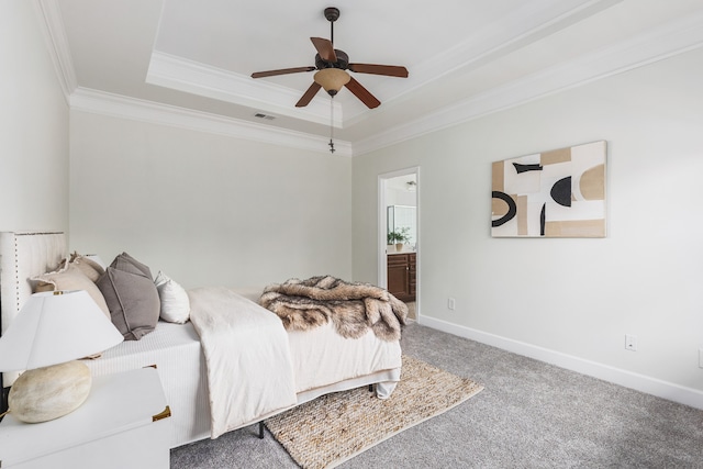 carpeted bedroom featuring ornamental molding, ensuite bathroom, ceiling fan, and a raised ceiling