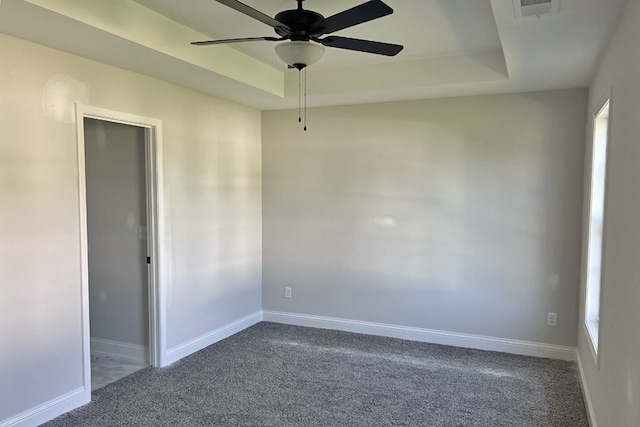 spare room featuring carpet flooring, a raised ceiling, and baseboards